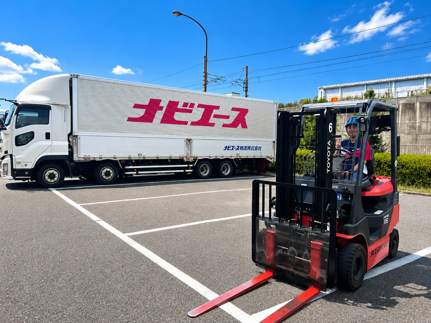 ナビエースの配送トラックのそばでフォークリフトを操作する社員